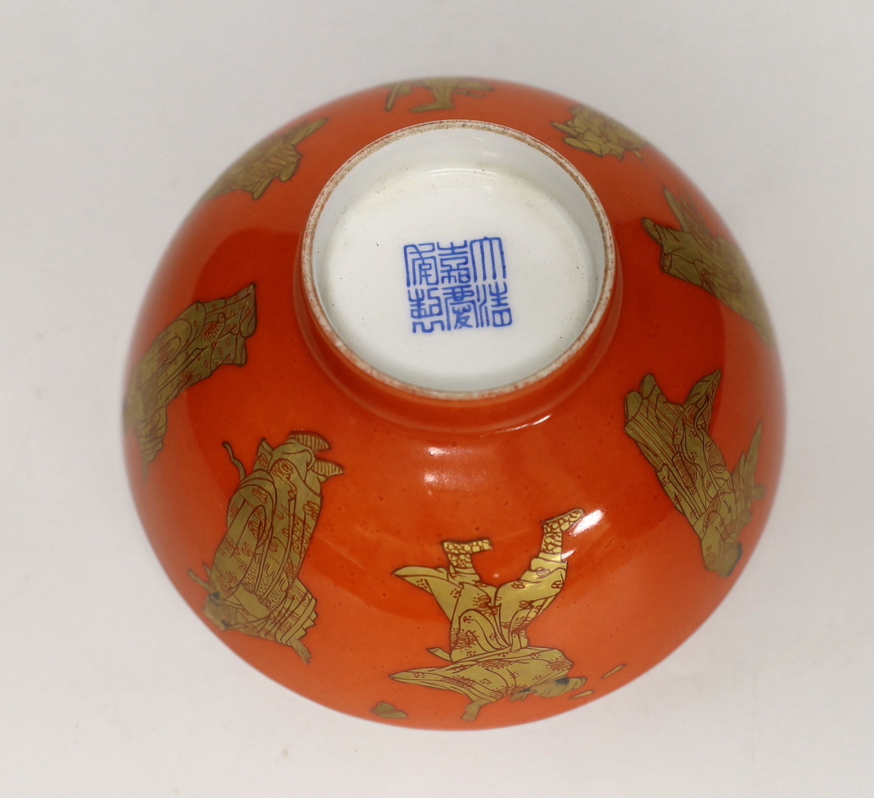 A Chinese coral red ground bowl, gilded with figures, 14cm diameter